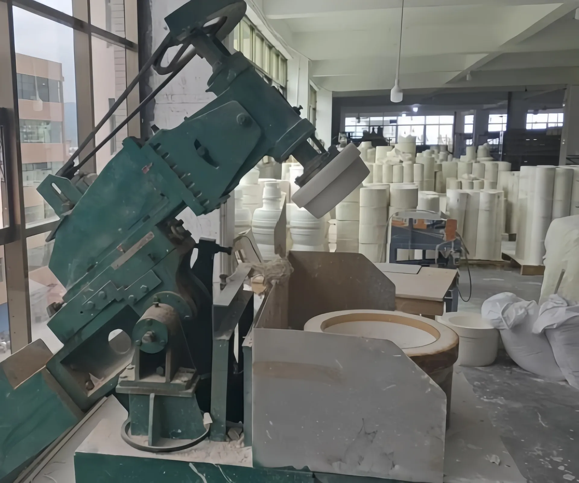 Eine Industriemaschine in einer Fabrikumgebung, umgeben von gestapelten zylindrischen Formen.