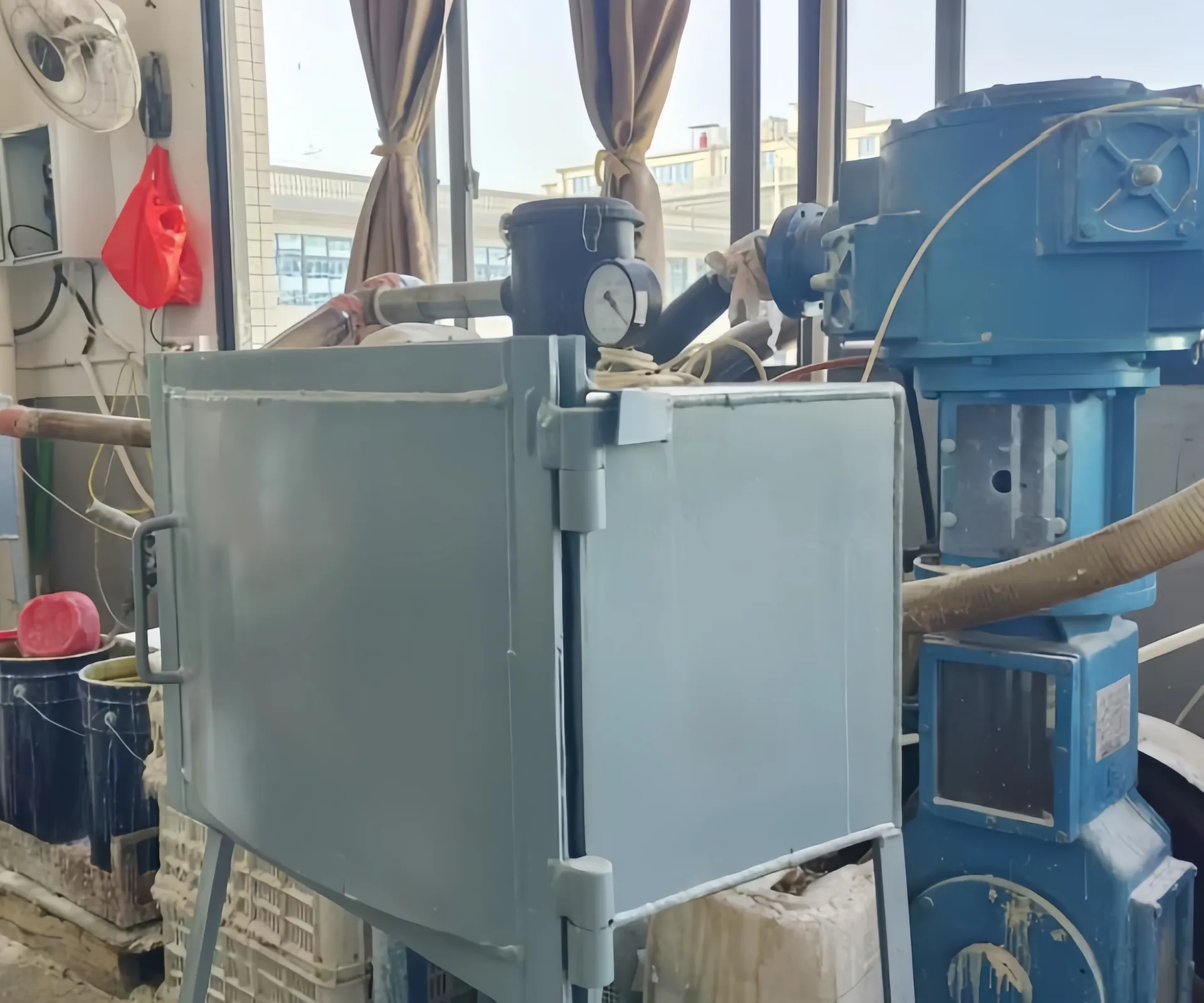 Eine Industriemaschine mit blauen Komponenten in einer Werkstatt, umgeben von verschiedenen Werkzeugen und Geräten.