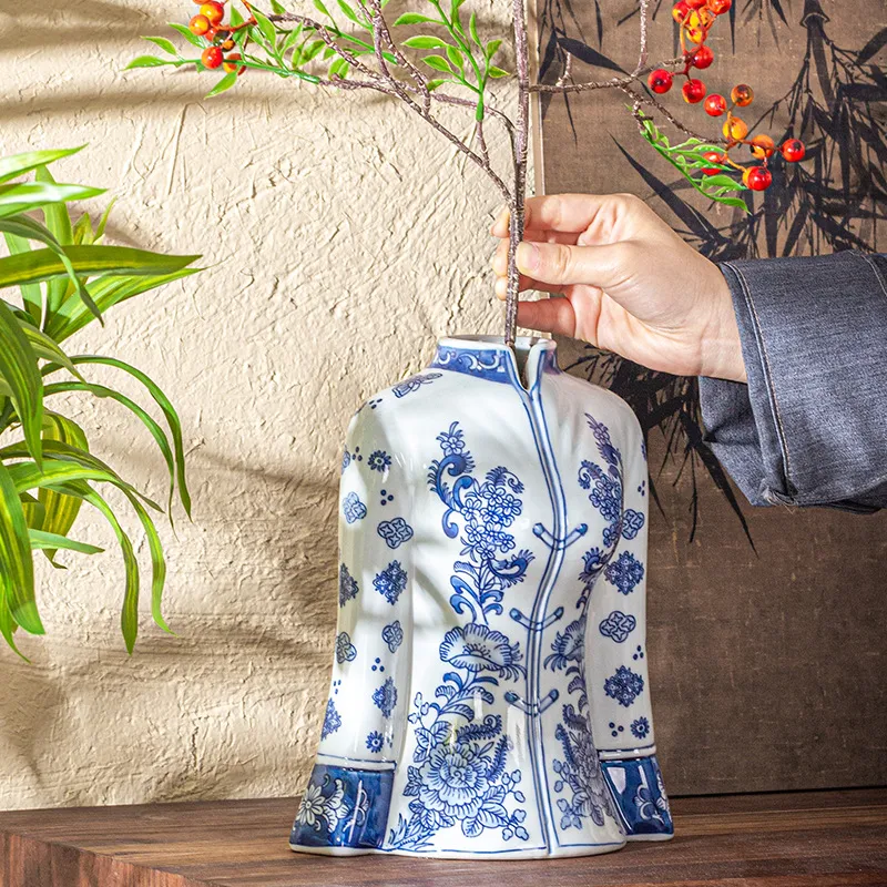 A vase shaped like a traditional Chinese jacket with blue floral patterns, filled with branches.