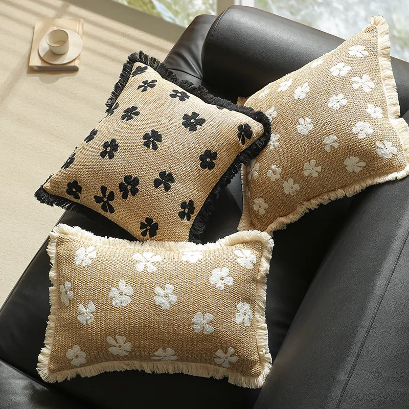 Trois coussins décoratifs à motifs floraux sur un canapé noir.