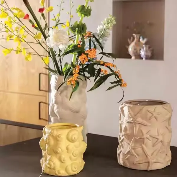 A collection of three decorative vases with textured designs, one holding a variety of flowers.