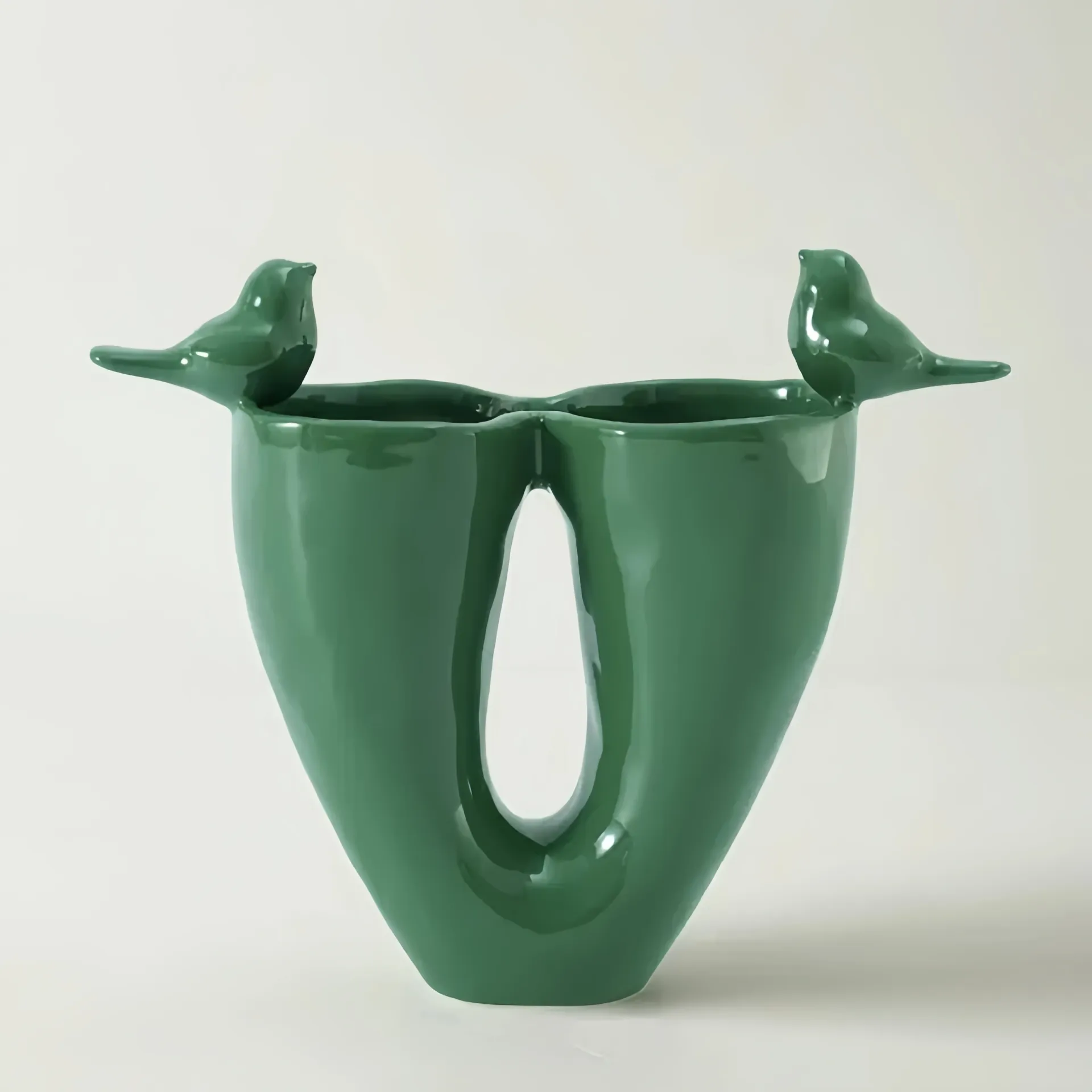 A green ceramic vase with bird-shaped details on top.
