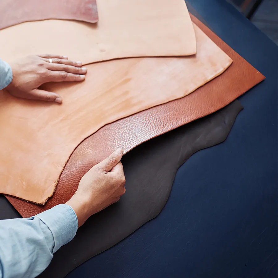 Person examining different shades of leather sheets with both hands.