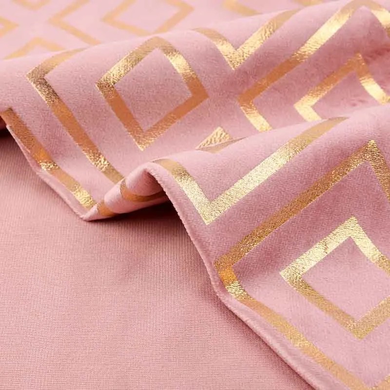 Close-up of pink fabric with a gold geometric pattern.