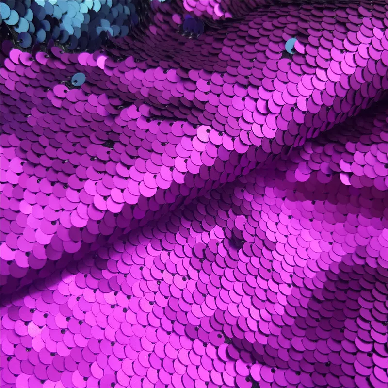 Close-up view of a fabric surface covered with shiny purple sequins.