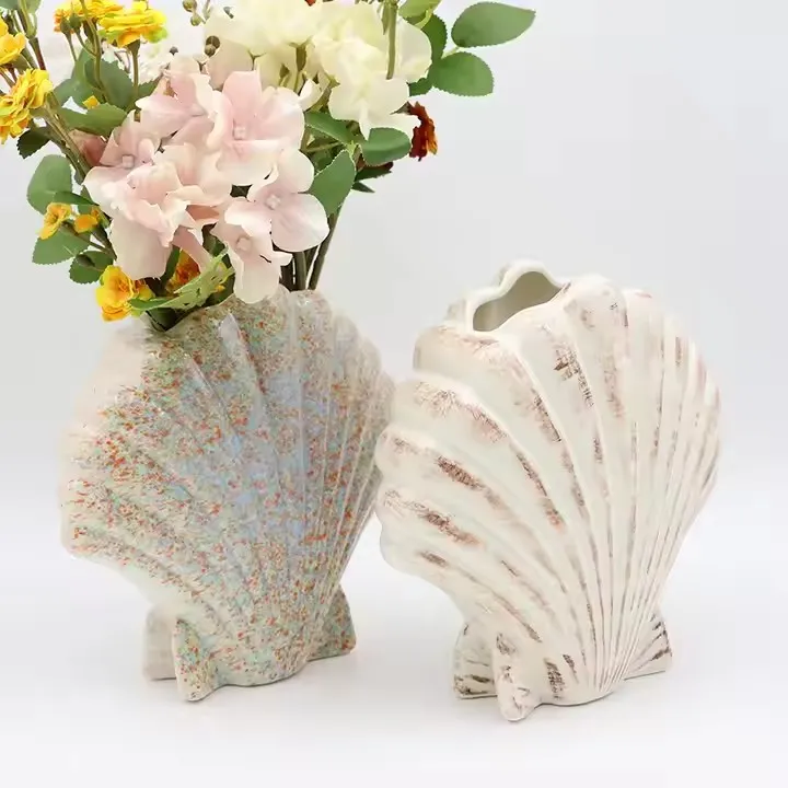 Two ceramic vases shaped like seashells, one with flowers.