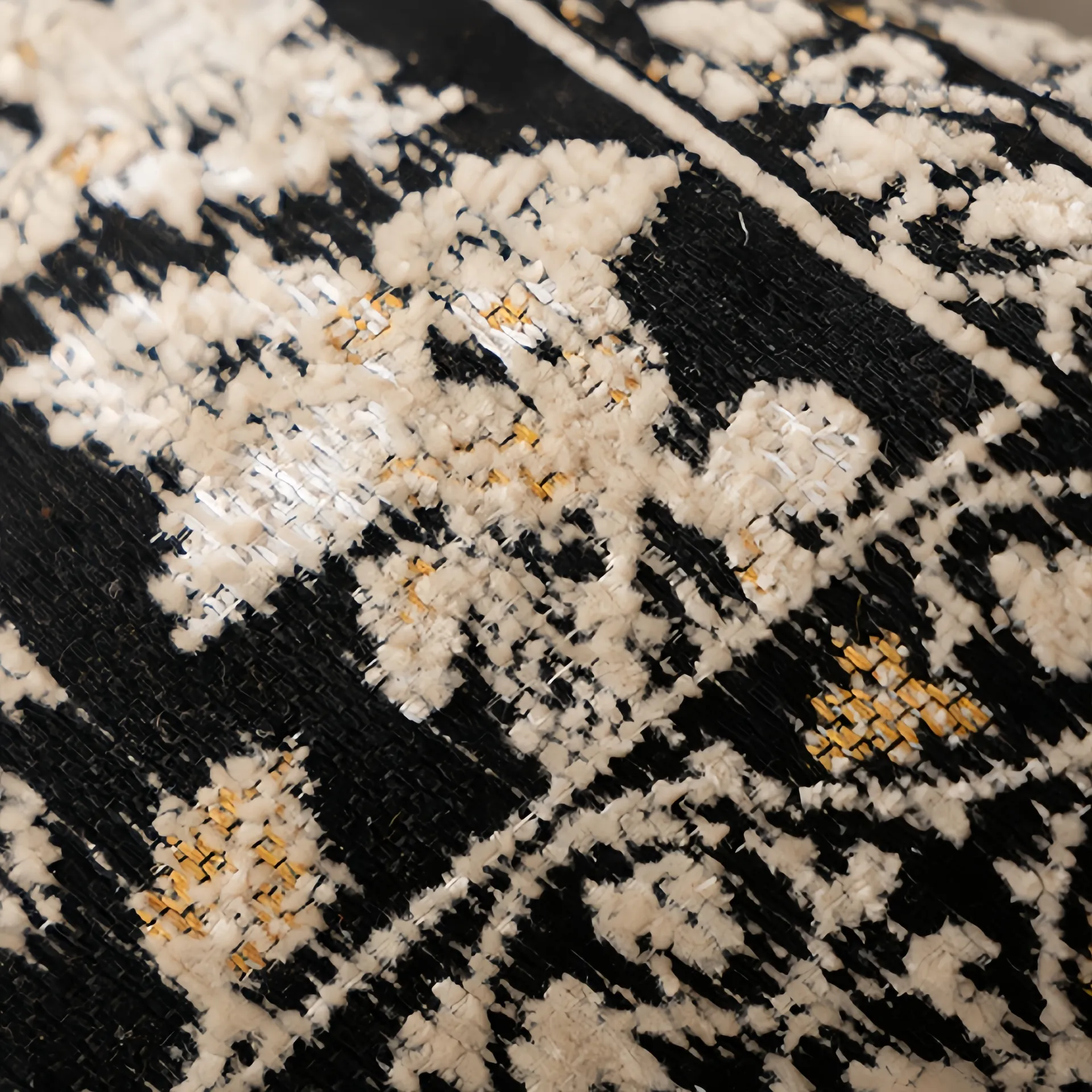 Close-up view of a textured fabric with black, white, and yellow patterns.