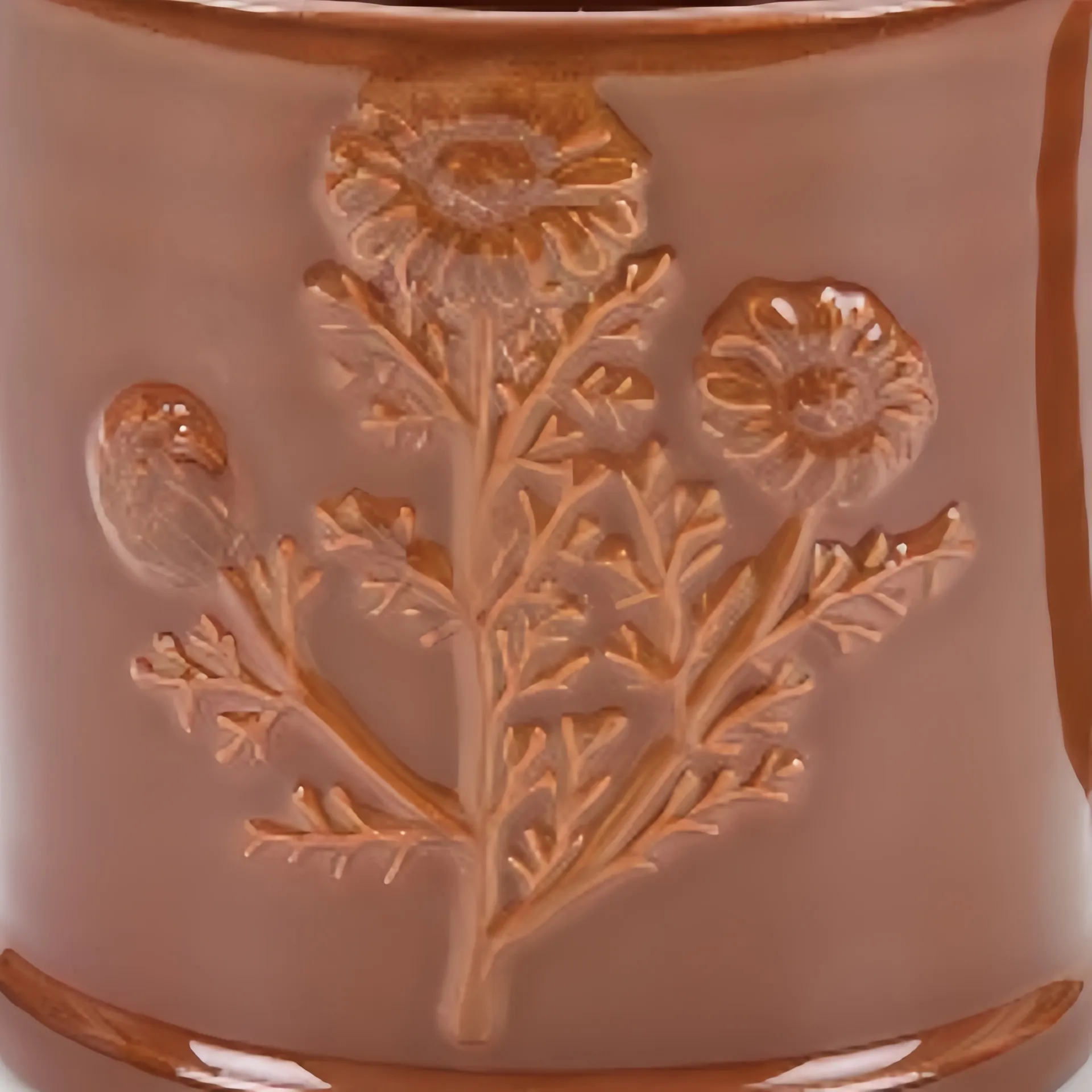 A close-up of a ceramic mug with an embossed floral design, featuring daisies and leaves.