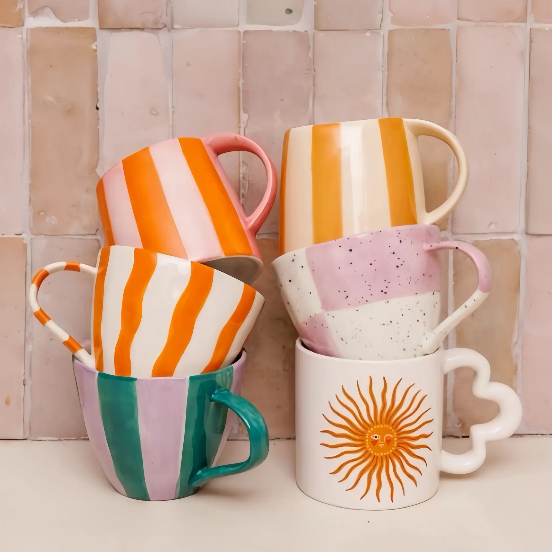 Stack of colorful mugs with various patterns against a tiled background.