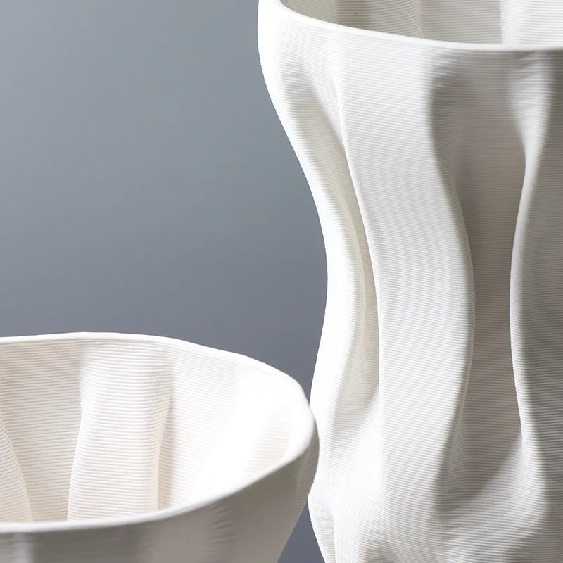 Close-up of two modern, white vases with smooth, curved surfaces against a gray background.