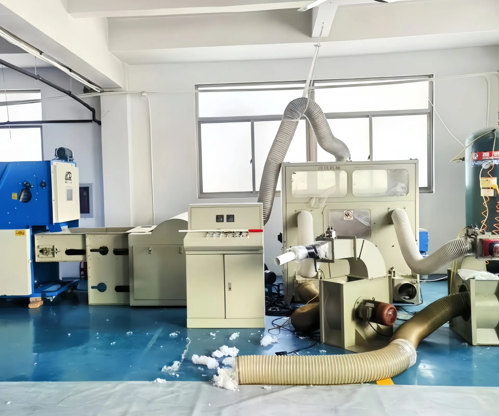 A room housing industrial machinery for fiber processing, featuring various connected machines with ducts and control panels.