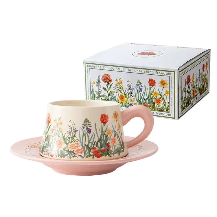 A teacup with a matching saucer featuring colorful floral designs alongside its box.