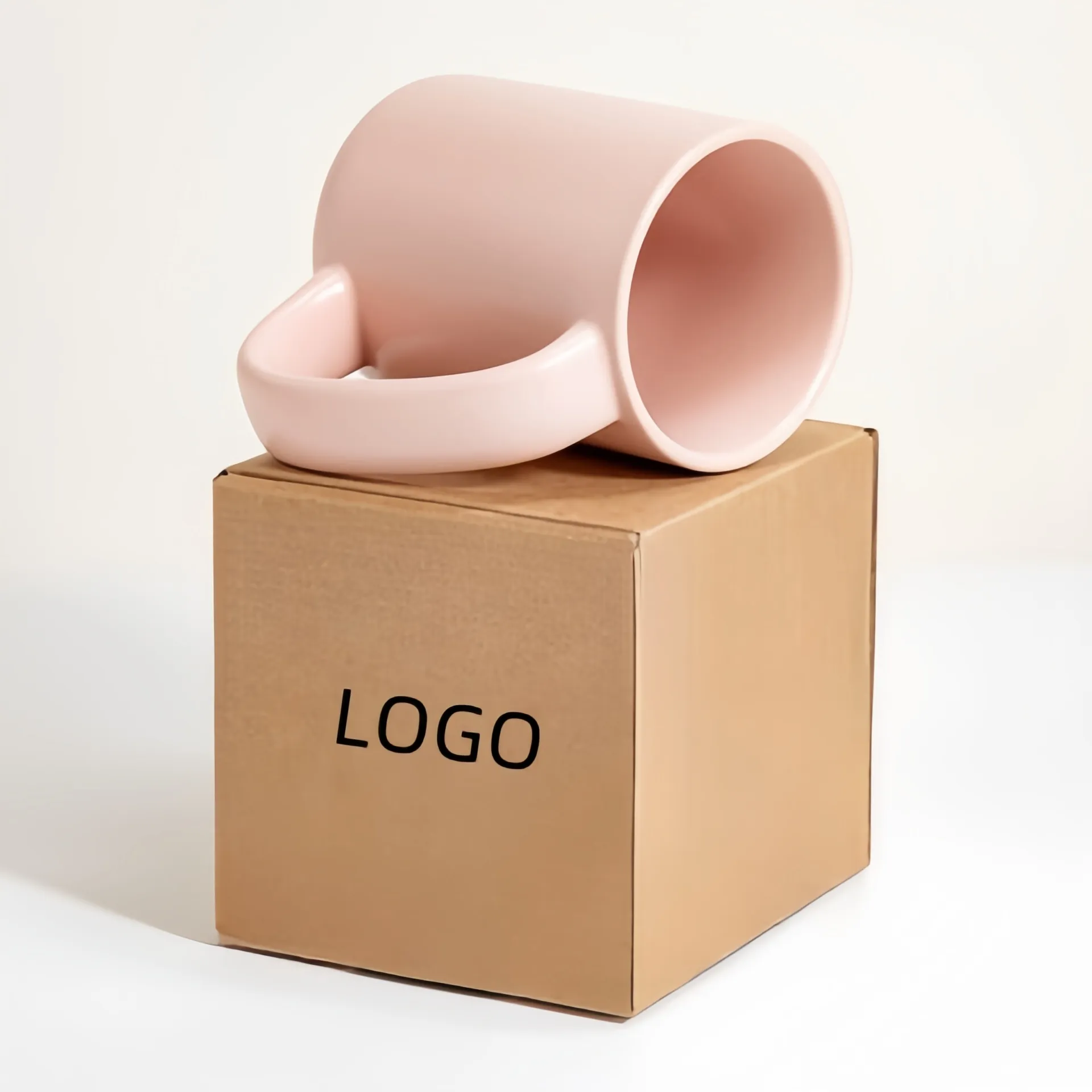 A pink mug resting on a brown cardboard box with the word 'logo' printed on the box.