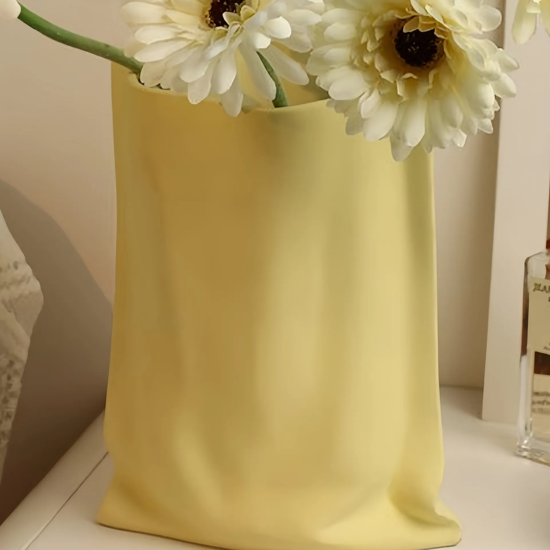 A yellow vase with white flowers placed on a shelf.