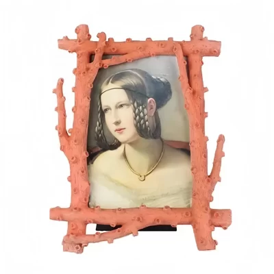 Klassisches Porträt einer Frau mit üppigem Haarschmuck in einem korallenartigen Rahmen.